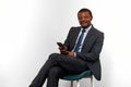 Smiling african american black man in business suit sitting on chair isolated on white background Royalty Free Stock Photo