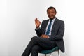 Smiling african american black man in business suit sitting on chair, OK gesture white background Royalty Free Stock Photo