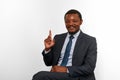 Smiling african american black man in business suit sitting on chair, pointing finger idea gesture Royalty Free Stock Photo