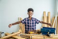 Smiling African-American boy carpenter spreading arms happily to show that the woodwork is placed on the table will try to succeed