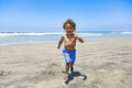 Smiling African American boy running and playing at the beach while on a family vacation. Royalty Free Stock Photo