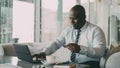 Smiling African American businessman in formal clothes paying online bill using his credit card and laptop in Royalty Free Stock Photo