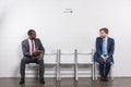 smiling african american businessman looking at scared colleague while waiting