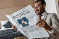 Smiling african american businessman in suit reading business newspaper