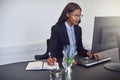 Smiling African American businesswoman taking notes while using Royalty Free Stock Photo