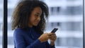 Smiling african american businesswoman texting mobile phone internet in office. Royalty Free Stock Photo