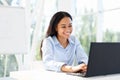 Smiling african american businesswoman working on laptop sitting at her desk in modern office Royalty Free Stock Photo