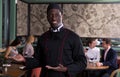 Smiling African American chef inviting to restaurant