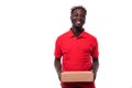 Smiling african american delivery man holding cardboard box and looking at camera isolated on white background Royalty Free Stock Photo