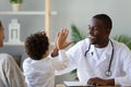 Smiling African American doctor giving high five to little boy Royalty Free Stock Photo