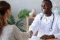 Smiling african American doctor handshake grateful female patient