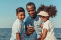 smiling african american father with adorable kids using smartphone