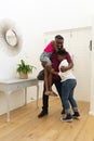 Smiling african american father returning home embracing son and daughter in hallway Royalty Free Stock Photo