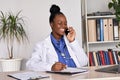 Smiling african female doctor physician holding phone talking on mobile at work. Royalty Free Stock Photo