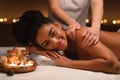 Smiling african girl enjoying back massage at romantic atmosphere Royalty Free Stock Photo