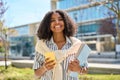 Smiling African American girl student walking in park using mobile phone. Royalty Free Stock Photo