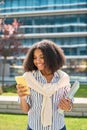 Smiling African American girl student walking in park using mobile phone. Royalty Free Stock Photo