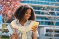 Smiling African American girl student walking in park using mobile phone. Royalty Free Stock Photo