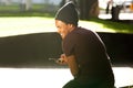 Smiling african american guy sitting in city park with cellphone Royalty Free Stock Photo