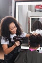 Smiling african american hairstylist drying hair