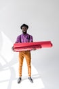 smiling african american in hat holding pink wrapping paper rolls in hands