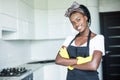 Smiling african american housewife in apron with arms crossed cleaning at home Royalty Free Stock Photo