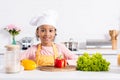 smiling african american kid in apron and chef hat preparing vegetables Royalty Free Stock Photo