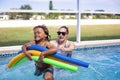 Smiling African American little boy playing in the swimming pool with his mother. Having fun playing with pool noodles in the sun Royalty Free Stock Photo