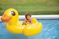 Smiling African American little boy playing in the swimming pool with a large inflatable duck. Royalty Free Stock Photo