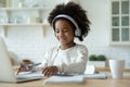 Smiling African American little girl wearing headphones studying at home Royalty Free Stock Photo