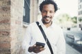 Smiling African American man in headphones looking to camera and listening to songs on his cell phone.Blurred background Royalty Free Stock Photo