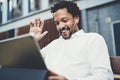 Smiling African American man in headphones making video call at sunny street on electronic touch pad,checking e-mail Royalty Free Stock Photo