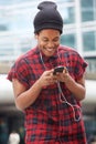 Smiling african american man listening to music with mobile phone and earphones in the city Royalty Free Stock Photo