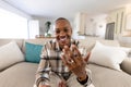 Smiling african american man showing wedding ring while sitting on sofa and in living room