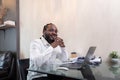 Smiling African American man sit at desk in home working on laptop, happy African American male look at camera posing Royalty Free Stock Photo