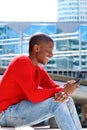 Smiling african american man sitting outside with cellphone Royalty Free Stock Photo