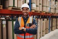 Confident african american man standing with folded arms in manufacturing unit with white helmet and uniform in factory