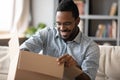 Smiling African American man wearing glasses unpacking parcel Royalty Free Stock Photo