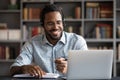 Smiling African American man wearing headphones looking at laptop screen