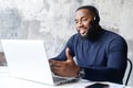 Smiling African-American man wearing headset using a laptop at office Royalty Free Stock Photo