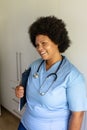 Smiling african american mid adult female nurse with stethoscope and clipboard standing in hospital Royalty Free Stock Photo