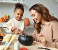 Smiling african american mother and child girl paint  Halloween pumpkins while sitting in cozy kitchen Royalty Free Stock Photo
