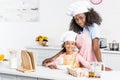 smiling african american mother and daughter in chef hats preparing dough Royalty Free Stock Photo