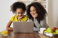 Smiling african american mother with her daughter using laptop in the kitchen. Royalty Free Stock Photo