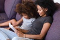 Smiling African American mother reading book with daughter