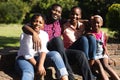 Smiling african american parents with daughter and son sitting embracing outdoors Royalty Free Stock Photo