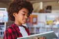 Smiling african american schoolboy reading book standing in school library Royalty Free Stock Photo