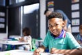 Smiling african american schoolboy working at desk in elementary school classroom, with copy space Royalty Free Stock Photo