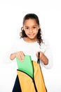 smiling african american schoolgirl putting book in backpack isolated on white.