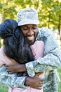 smiling african american soldier in military uniform cuddling girlfriend